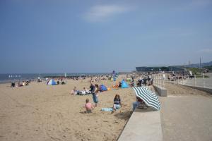 a group of people on a beach with an umbrella at One bedroom holiday apartment Colwyn Bay in Colwyn Bay