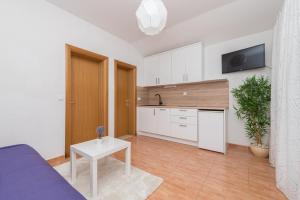 una cocina con armarios blancos y una mesa en una habitación en Apartments Tila, en Drasnice