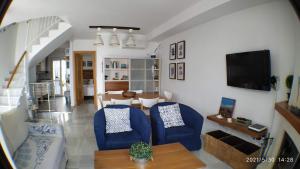 salon z 2 niebieskimi krzesłami i telewizorem w obiekcie La Casa De La Playa w mieście Chilches