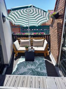 een patio met 2 banken en een parasol bij Vakantiehuis De Oude Bakkerij in Katwijk aan Zee