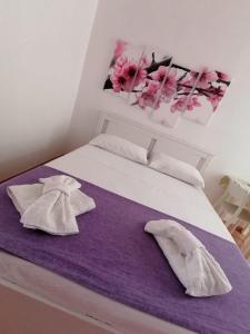 a bed with two pillows and a purple blanket at Sognando Lampedusa in Lampedusa