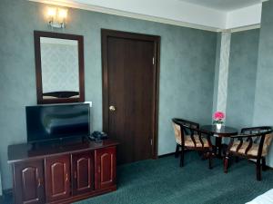 a hotel room with a television and a table with chairs at Hotel Smarald in Eforie Nord