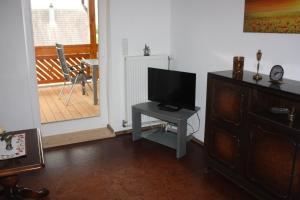 a living room with a tv and a table with a television at Gästehaus Wacker in Ringsheim