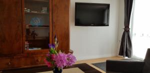 a vase with purple flowers in a living room with a tv at Stara Kuźnia in Sztutowo