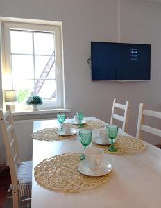 a dining room with a table with a television on the wall at Apartament 39 in Karpacz