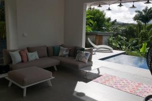 uma sala de estar com um sofá e uma piscina em Villa Kumquat, avec piscine Clévacances 4 clés em Petit-Bourg