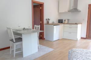 a kitchen with white cabinets and a table with two chairs at Cantinho da Quintã in Mesão Frio +5 photos