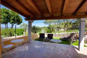 a patio with tables and chairs under a wooden roof at La Casa in Collina - affittacamere con vista mare in Lu Lioni
