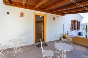 une chambre avec des tables et des chaises sur une terrasse dans l'établissement La Casa in Collina - affittacamere con vista mare, à Lu Lioni