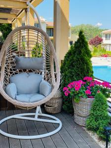 une chaise en osier assise sur une terrasse couverte fleurie dans l'établissement Arapya Beach Apartment, à Tsarévo