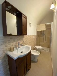 een badkamer met een wastafel, een toilet en een spiegel bij Dimora di nonno Livio in Santo Stefano di Sessanio