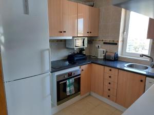 a kitchen with a white refrigerator and a sink at BRAVAHOLIDAYS-410-Neptuno in Blanes