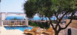 a swimming pool with two chairs and a tree at Villa Zante Avia in Planos