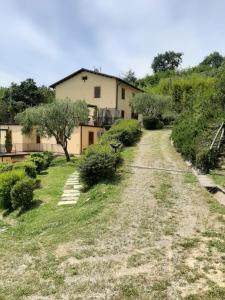 eine Feldstraße, die zu einem Haus mit Bäumen und Sträuchern führt in der Unterkunft Tenuta degli Obizzi in Montecarlo