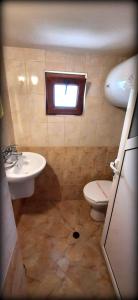een badkamer met een wastafel, een toilet en een raam bij Лорета-Камен бряг in Kamen Bryag