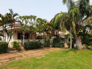 a house with palm trees in front of a yard at Tiger@home in Nakhon Ratchasima