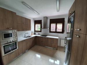 una cocina con armarios de madera y electrodomésticos de acero inoxidable en Apartament Vall de Ribes, en Ribes de Freser