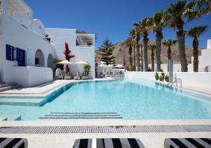 une piscine bordée de palmiers et un bâtiment blanc dans l'établissement Kouros Village Hotel - Adults Only, à Perissa