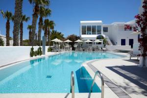 a large swimming pool with chairs and a building at Kouros Village Hotel - Adults Only in Perissa