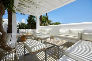 a patio with white chairs and tables and a couch at Kouros Village Hotel - Adults Only in Perissa