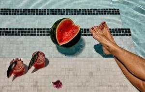 a person in a swimming pool with a slice of watermelon at Kouros Village Hotel - Adults Only in Perissa
