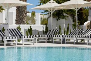a group of chairs and umbrellas next to a swimming pool at Kouros Village Hotel - Adults Only in Perissa