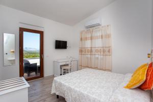 a bedroom with a bed and a window and a desk at La Casa in Collina - affittacamere con vista mare in Lu Lioni