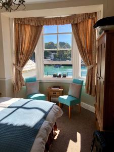 um quarto com uma cama, 2 cadeiras e uma janela em The Warwick em Weymouth
