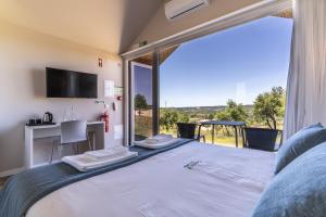 - une chambre avec un grand lit et une grande fenêtre dans l'établissement Gavião Nature Village, à Gavião