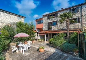 une terrasse avec une table, des chaises et un parasol dans l'établissement Apartmani Mirjana Umag, à Umag