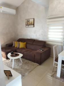 ein Wohnzimmer mit einem braunen Sofa und einem Tisch in der Unterkunft Apartmani Stijepovic in Podgorica