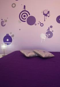 a bedroom with a bed with purple sheets and planets on the wall at Arrifana Guest House in Aljezur