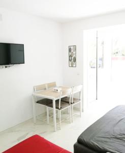 a white room with a desk and a tv at Babylon Tourist Apartments in Benalmádena