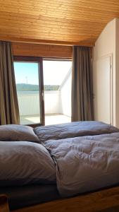 two beds in a room with a large window at AUSZEIT in Obertal