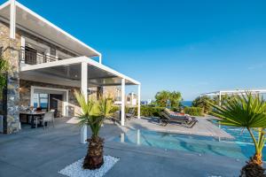 ein Haus mit einem Pool und einer Terrasse mit Palmen in der Unterkunft Achlia Beach Villa in Achlia