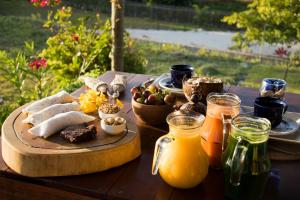 a wooden table topped with plates of food and orange juice at Villa Sabiá - Eco Bungalows in Prea