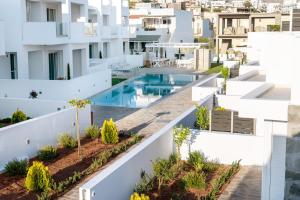 an aerial view of a white apartment building with a swimming pool at Makrygialos Long Beach Villa 1 in Makry Gialos