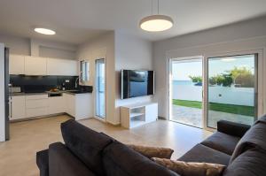 a living room with a couch and a tv and a kitchen at Makrygialos Long Beach Villa 1 in Makry Gialos