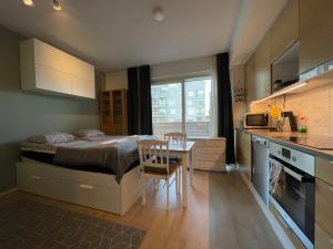 a bedroom with a bed and a table and a kitchen at The Seaside Apartment Turku in Turku