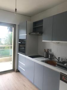 a kitchen with white cabinets and a sink and a window at Appartement centre Barcelonnette in Barcelonnette