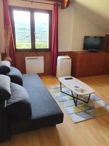 ein Wohnzimmer mit einem Sofa und einem Tisch in der Unterkunft Chez Gilles et Eveline in Cruet