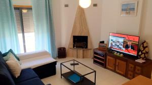 a living room with a couch and a flat screen tv at Apartamento Varandas de Pêra in Pêra