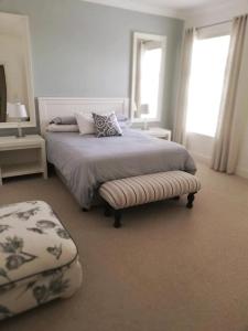 a bedroom with a bed with a ottoman and two windows at A home for the ultimate West Coast beach holiday in St Helena Bay