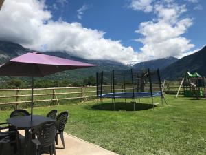 une table et des chaises avec un parasol et un trampoline dans l'établissement maisonnette entre lac de Passy et montagnes, à Domancy