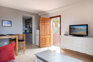 sala de estar con TV y cocina con mesa en Oasis Royal, en Corralejo