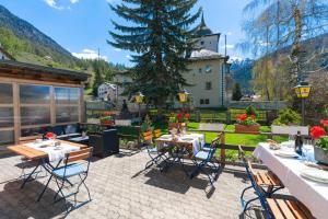 a patio with tables and chairs and a house at Hotel Alpina in Zernez