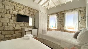 a bedroom with two beds and a stone wall at Oberj d'Azur Alaçatı in Alaçatı