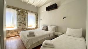a bedroom with two beds and a stone wall at Oberj d'Azur Alaçatı in Alaçatı