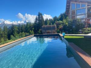 a swimming pool in a yard with mountains in the background at Chalet Béla Vya in Arc 1600