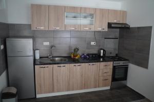 uma cozinha com armários de madeira, um lavatório e um frigorífico em apartman Vidović em Livno